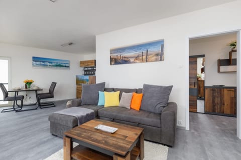 A bright living room with a gray sofa, colorful cushions, and a wooden coffee table, complemented by a modern decor style.