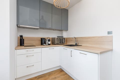 A sleek kitchen with white cabinetry, light wooden countertops, and a neat arrangement of appliances and shelves.