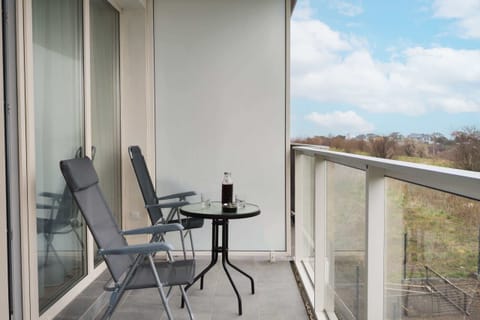 A balcony view showcasing an outdoor seating area with two chairs and a small table, perfect for enjoying the fresh air.

