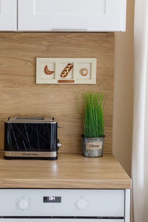 A wooden kitchen countertop with a built-in electric stove and a few decorative items on the shelf above. The warm wood tones contrast nicely with the sleek cabinetry.