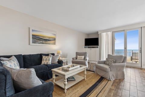 Living Space with a Navy Sectional and Two Swivel Chairs Positioned Around a Flat Screen Smart TV