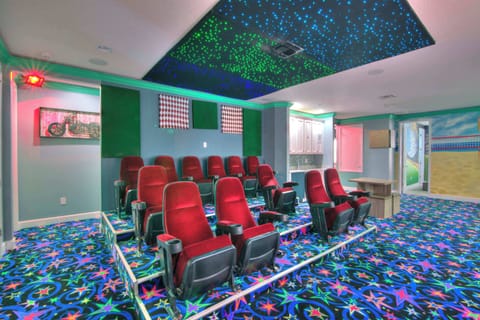 Enjoy a private movie night in this vibrant home theater with starry ceiling and cozy seating.