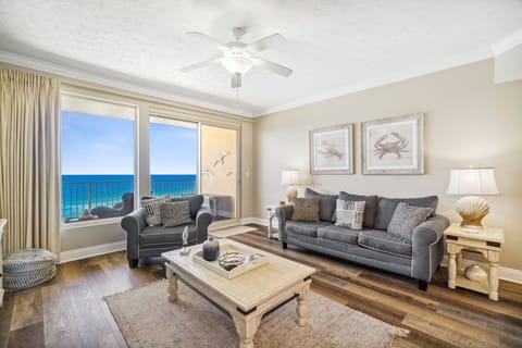 Bright living room w/ plush seating, coastal art & natural light pouring through large windows.