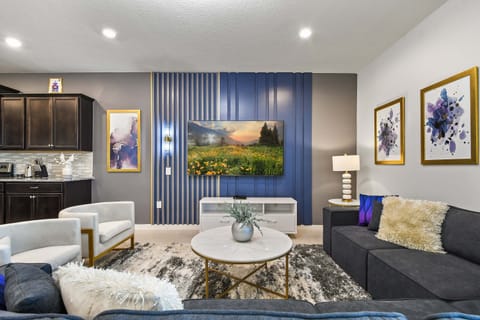 Stylish living room with sleek TV wall, cozy seating, and modern gold accents