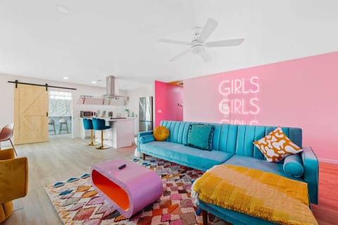 Bright living area w/ playful decor, cozy seating, & pops of pink throughout.