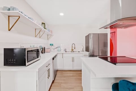 Sleek kitchen w/ clean lines, white cabinetry, & modern appliances.