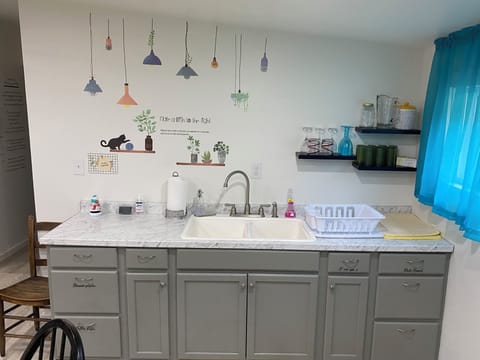 Sink area with dinnerware silverware cups and bowls in drawers