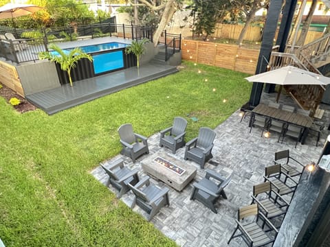 Lush backyard with palms trees, firepit, summer kitchen and shipping cont pool