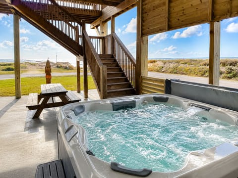 Covered private hot tub under the home with Gulf-facing views, patio space, picnic table, and relaxing coastal vacation setting.