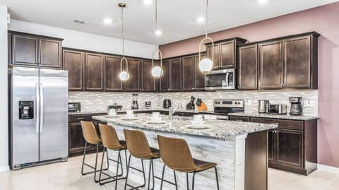 Sleek modern kitchen with granite island, stainless appliances, and pendant lighting.