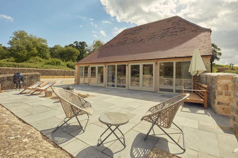 Large patio with chairs, outside sofa bed and charcoal BBQ
