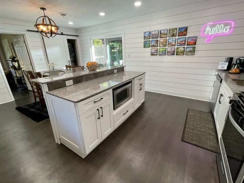 Neon ‘Eat’ sign and chic open shelving add playful flair to meal prep.