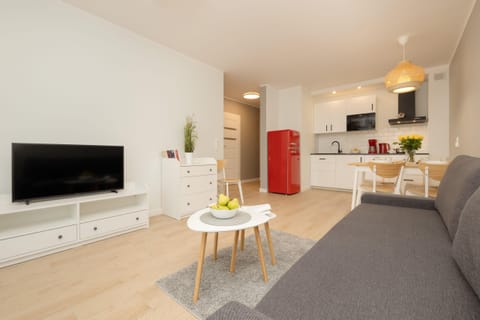 A wide view of the living and dining area, featuring a gray sofa, modern furniture, and bright, airy decor.
