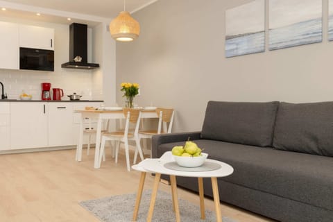 A modern living room with a gray sofa, a coffee table, and a dining area connected to the open-plan kitchen, creating a functional and stylish space.
