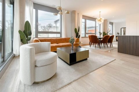 Elegant living and dining area featuring designer furniture, floor-to-ceiling windows, and a bright, welcoming atmosphere