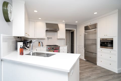 Cook your favorite meals in this bright, modern kitchen featuring premium stainless steel appliances and sleek white countertops.