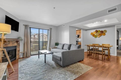 The living room is a bright light-filled room with a cozy fireplace and access to an outdoor balcony.