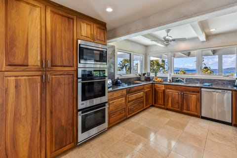 Cook with ocean views in a chef’s kitchen featuring koa wood and premium appliances.