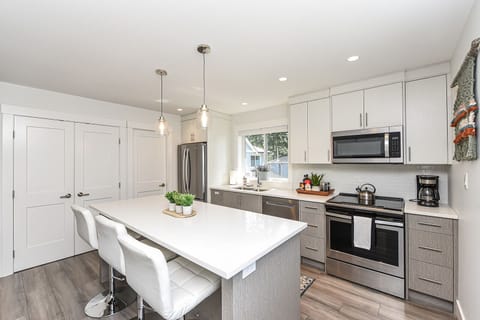 Modern kitchen with stainless steel appliances and quartz countertops. 