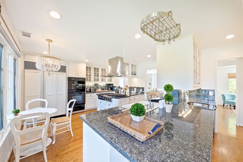 Spacious gourmet kitchen with granite countertops, stainless steel appliances, and a stunning chandelier centerpiece.