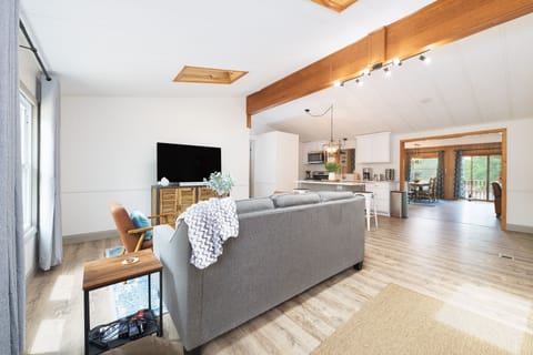 Spacious living room with vaulted ceilings and skylights, plus a 55" smart TV.