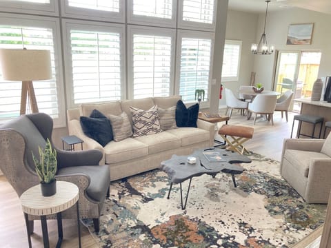 Large living area with television open to kitchen/dining and backyard.