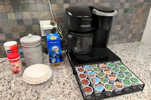 Coffee station with coffee brewer, Keurig pods, and various coffees supplies.