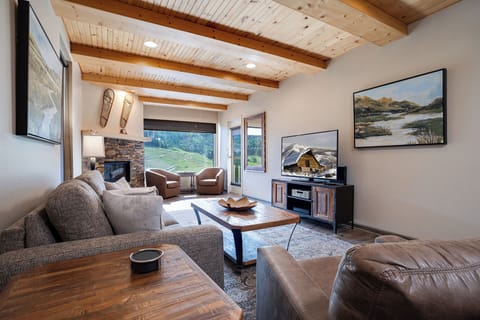 Unwind in this beautifully designed living room where exposed beams meet modern comfort, perfect for movie nights by the fireplace.