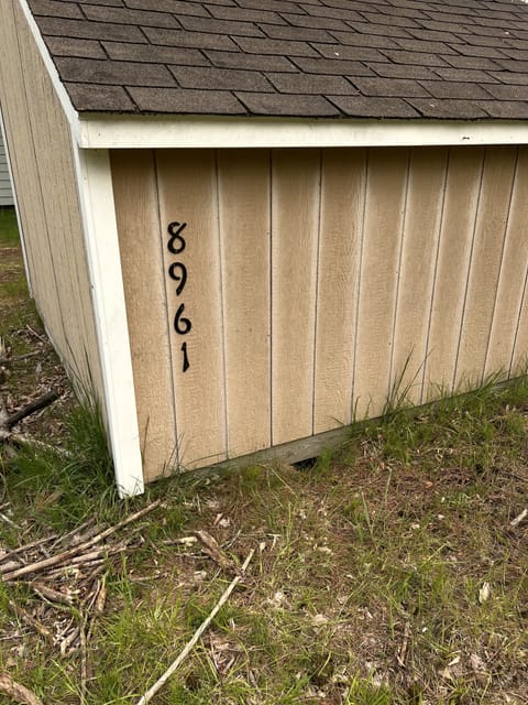 Shed seen from the road with address numbers and you approach the home.