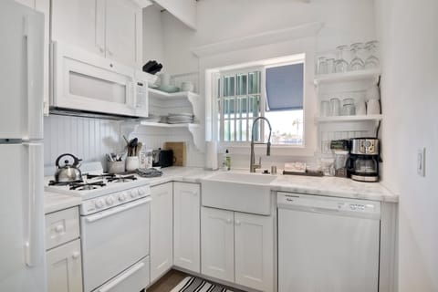 Kitchen area with gas stove/oven. Lots of dishes, pots and pans.