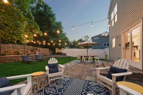 Fenced-in backyard featuring Polywood furniture and café string lights overhead.