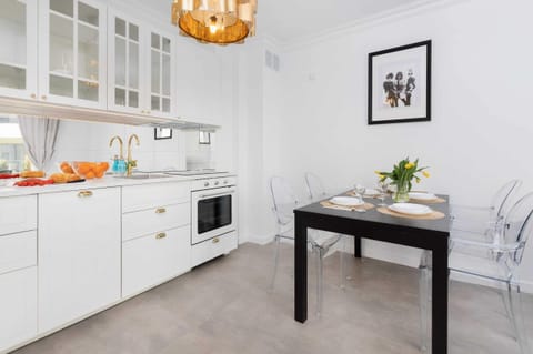 A modern kitchen with white cabinetry, a dining table, and chic decor, blending functionality with aesthetics.
