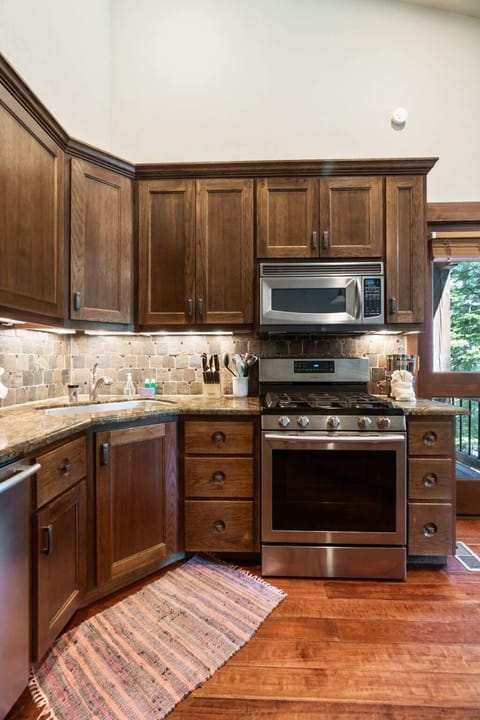The kitchen features ample cabinet space, lovely granite countertops, stainless steel appliances, and a full range of cookware