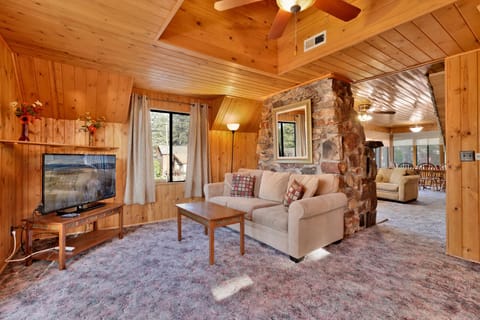 Cozy mountain living room with a stone fireplace, comfy seating, and smart TV—perfect for relaxing evenings, movie nights, and warm cabin vibes after outdoor adventures.