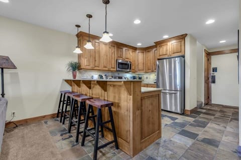 The fully equipped kitchen features stainless steel appliances, classic wood cabinets, and seating for four at the kitchen bar.