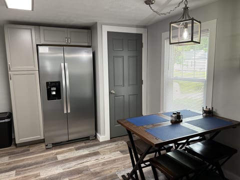 Kitchen area with new stainless refrigerator and dining table for four