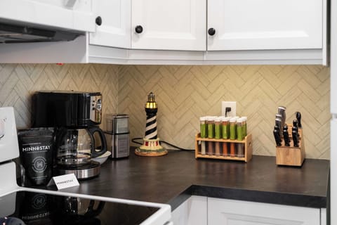 Start your morning right with fresh coffee from your fully equipped kitchen, featuring elegant herringbone backsplash and quality appliances for memorable meals.