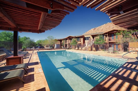 Lounge poolside under shaded pergolas in desert sunshine.