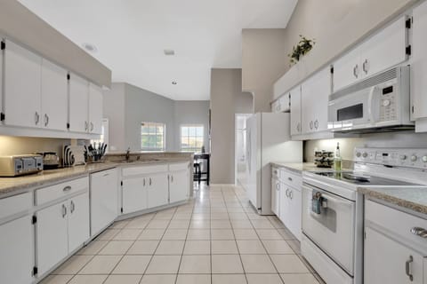Sunlight pours through the expansive windows, infusing the kitchen with a natural radiance.