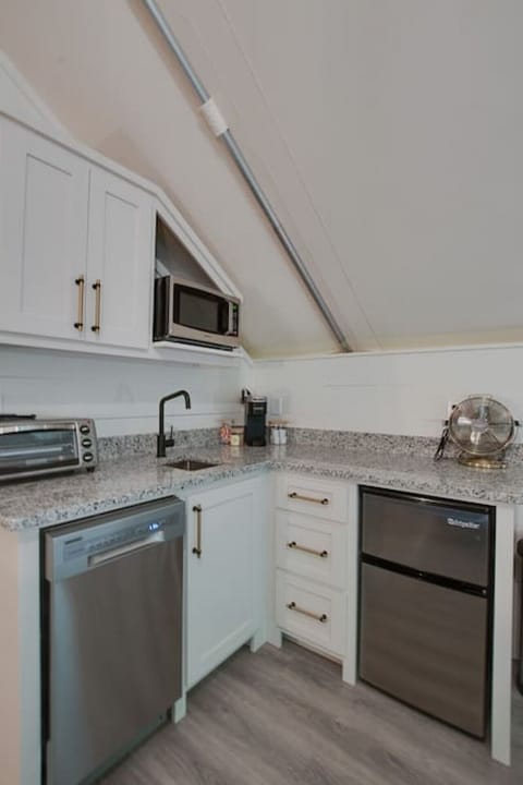 Well-equipped glamping tent with a modern kitchenette, including a dishwasher, fridge, and coffee maker, perfect for enjoying the comforts of home in a nature-filled setting.