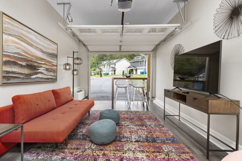 Converted garage lounge features a sleep sofa, TV, and table perfect for games.
