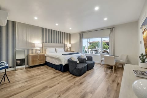 Bright bedroom w/ large windows, cozy bed & seating area for relaxing mornings