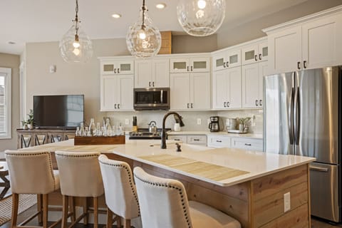 Sleek open kitchen w/ stainless steel appliances & granite island for 4 dining.