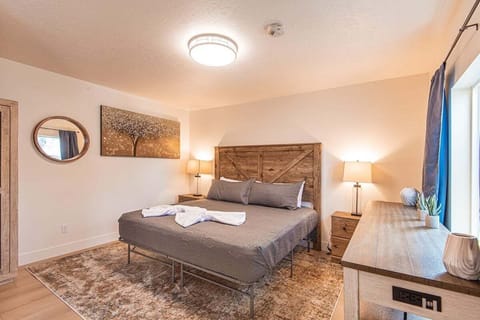 Comfortable bedroom with queen bed, warm lighting, nightstands with lamps, and modern furnishings.