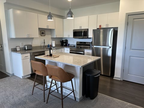 Modern kitchen with granite countertops, stainless steel appliances, and tons of kitchenware