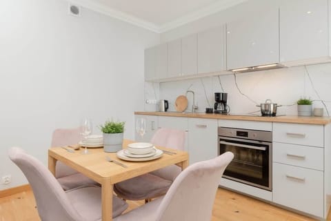 An open-concept kitchen with white cabinets, modern appliances, and a dining table with elegant chairs.