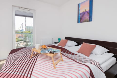 A sunny bedroom with a comfortable double bed, vibrant red-striped bedding, and modern decor.