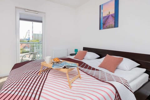 A sunny bedroom with a comfortable double bed, vibrant red-striped bedding, and modern decor.