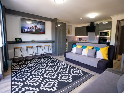 Features a chic color palette of gray and white, creating a sleek and sophisticated ambiance. Sink into the plush sofa adorned with modern pillows, adding a touch of flair to the contemporary decor. The room is bathed in natural light, highlighting the room's beauty.