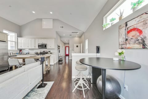 Open concept living room, dining room, and kitchen, hallway leads down to bedrooms, red door opens to the back deck.